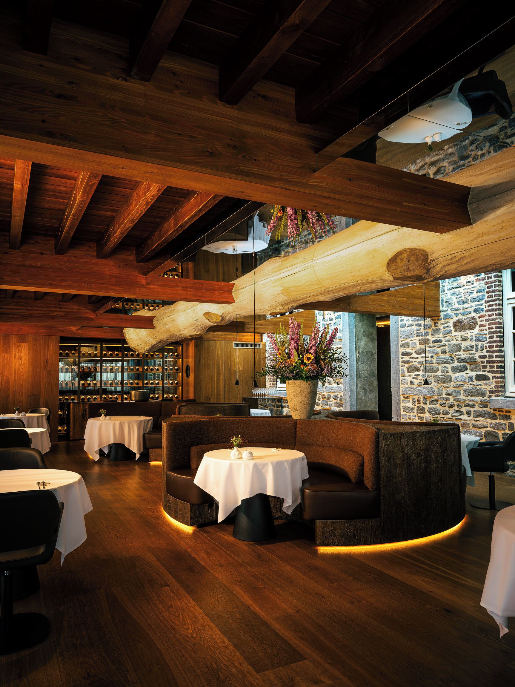A restaurant interior with wooden beams, stone walls, and tables with white tablecloths.