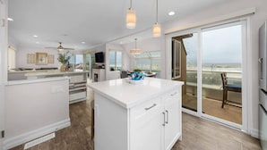 A modern kitchen with a central island, pendant lighting, and a view to the outside. - Panoramic Ocean View Huge Rooftop Deck - Sleeps 8 (San Diego)