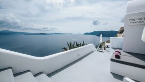 A modern, white-designed outdoor area with a view of the sea and distant islands.