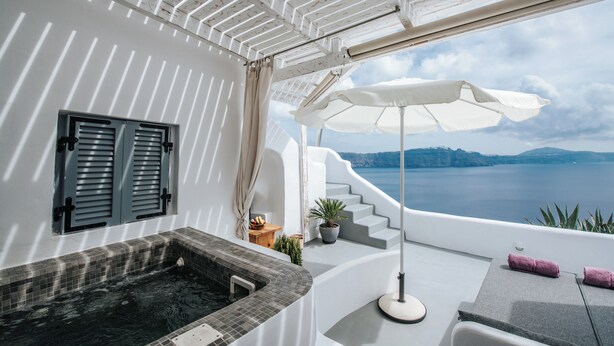 A modern bathroom with a bathtub, a shower, and a view of the sea.
