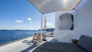 Ein moderner Balkon mit Meerblick, einer Couch und einem Tisch mit Stühlen.
