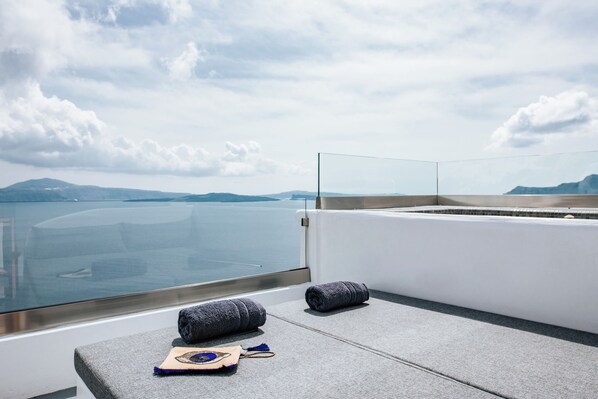 A balcony with a view of the sea and mountains, featuring a towel and a small bag.