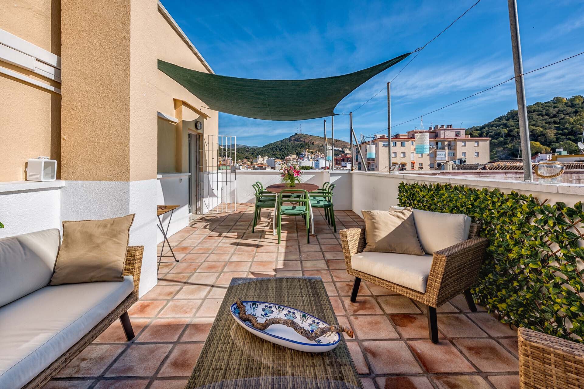Una terraza con un sofá, sillas, una mesa y un plato decorativo.
