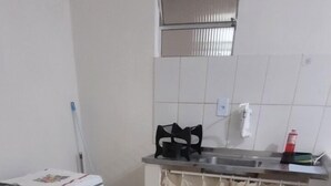 Et lille køkken med gasblus, vask og en lille bordplade.