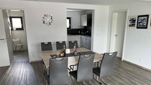 Un comedor moderno con una mesa de madera, seis sillas y un reloj de pared.