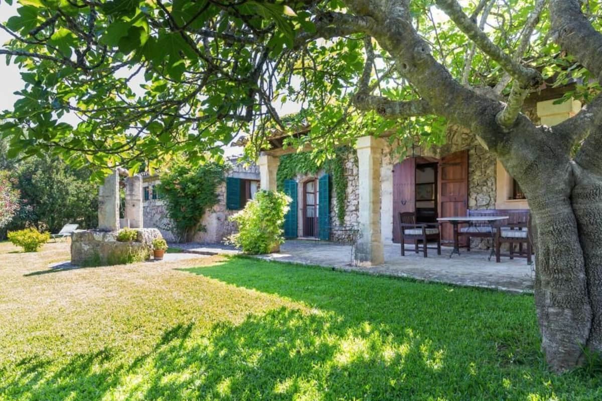 A traditional stone building with a covered outdoor seating area, surrounded by well-maintained greenery.