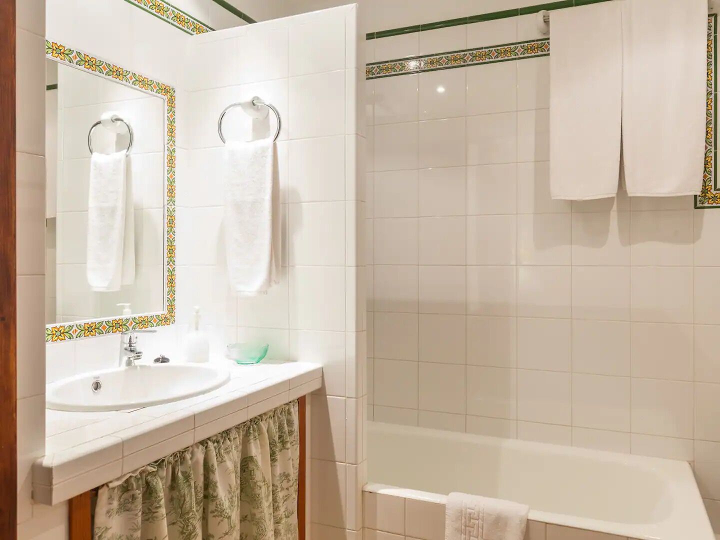 A bathroom with a sink, mirror, and bathtub.