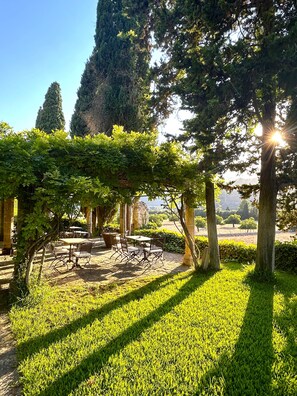 Un giardino con una pergola, tavoli e sedie.