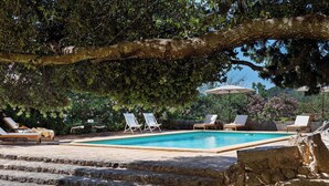 A pool area with stone steps leading to a pool, surrounded by lounge chairs and umbrellas. - Fangar Agroturismo (Campanet)