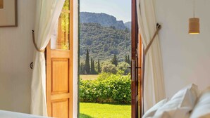An open bedroom with a view of a green landscape and a mountain. - Fangar Agroturismo (Campanet)