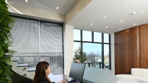 A modern office space with a large window, a desk with a computer, and a white couch. - Aristo (Artashat)