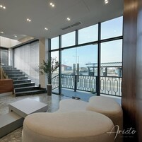 Un moderno vestíbulo de hotel con una escalera, un área de descanso y ventanas amplias con vista a la ciudad.