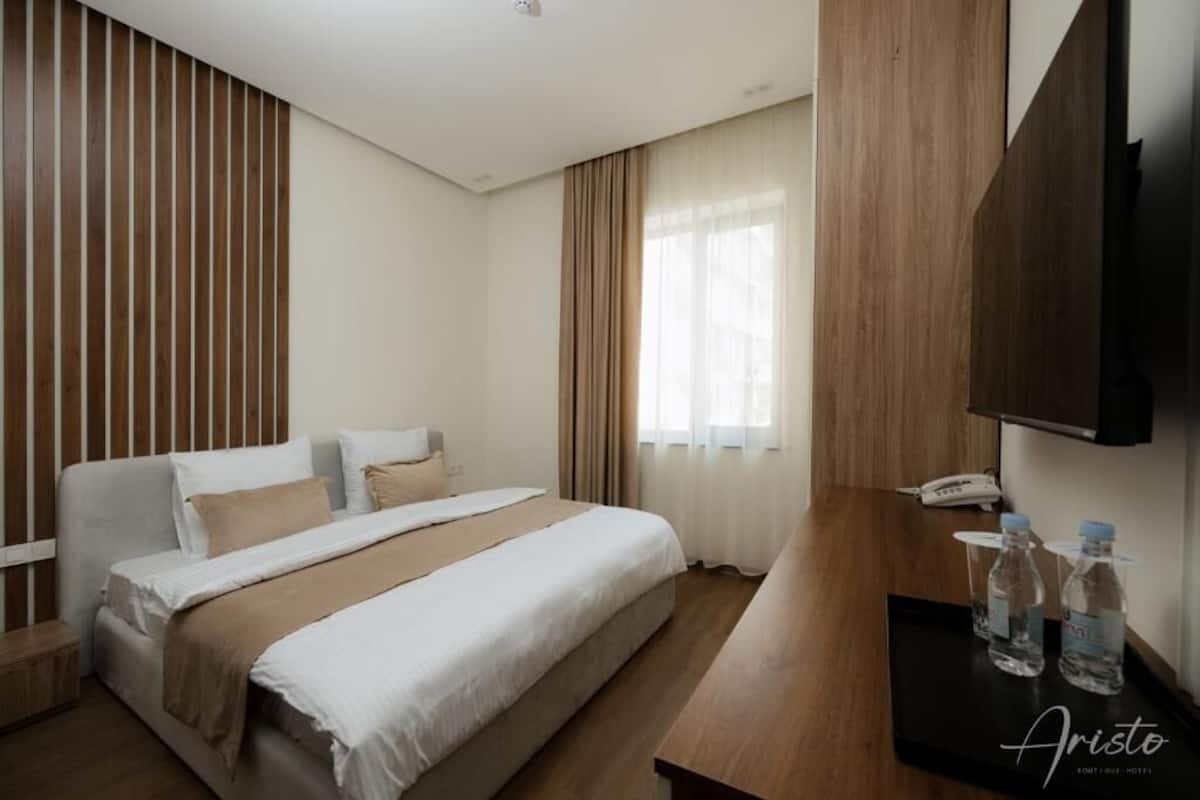 Ein Hotelzimmer mit einem Bett, einem Holztisch und einem Telefon.