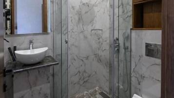 Un baño moderno con ducha acristalada, lavamanos blanco y retrete.