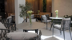 A modern dining area with round tables and wicker chairs, a wooden wall with vertical slats, and a staircase in the background. - Aristo (Artashat)