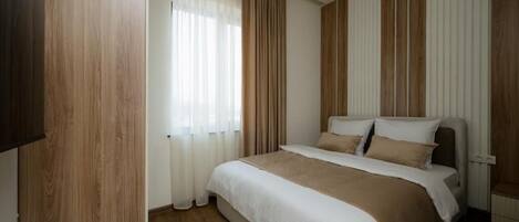 A hotel room with a bed, curtains, a telephone, and wooden paneling.