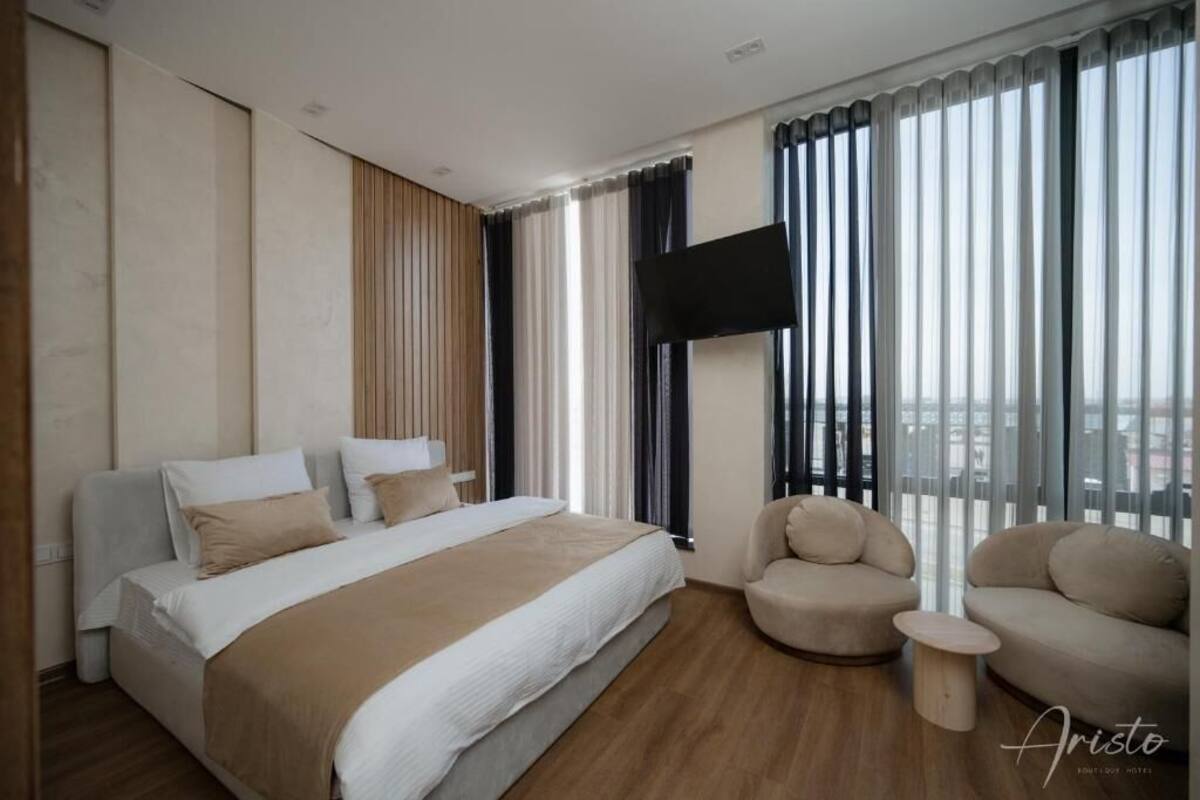 Ein modernes Hotelzimmer mit einem großen Bett, einem Flachbildfernseher, einer Couch und einem kleinen Beistelltisch.
