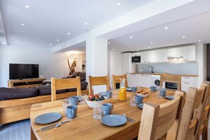 Ein modernes Wohnzimmer mit Essbereich, einer Küche und einem Fernseher.