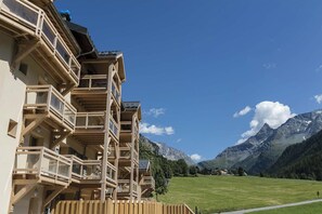 Ein mehrstöckiges Gebäude mit Balkonen vor einer Bergkulisse.