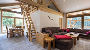 A spacious living area with a wooden staircase, a sofa set, and a dining table. - Résidence Chalet Les Amis (Peisey-Nancroix)