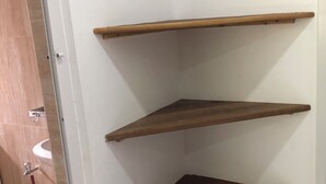 A bathroom with three wooden shelves, a white sink, and a red mop. - Misonobarini Sweet Villa (Nungwi)