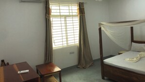 A bedroom with a bed, a desk, a chair, a ceiling fan, and a window with curtains. - Misonobarini Sweet Villa (Nungwi)