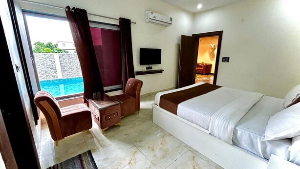 Habitación de hotel con cama, escritorio, silla, televisor y aire acondicionado.