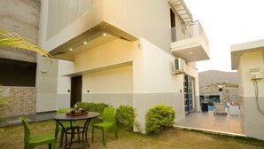 Una casa moderna con un patio, mobiliario exterior y vistas a la montaña.