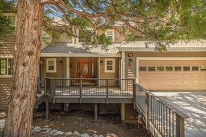 A two-story house with a covered porch, a garage, and a tree in the foreground.