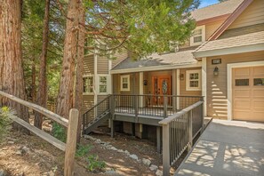 A two-story house with a front porch, a garage, and a wooden deck.