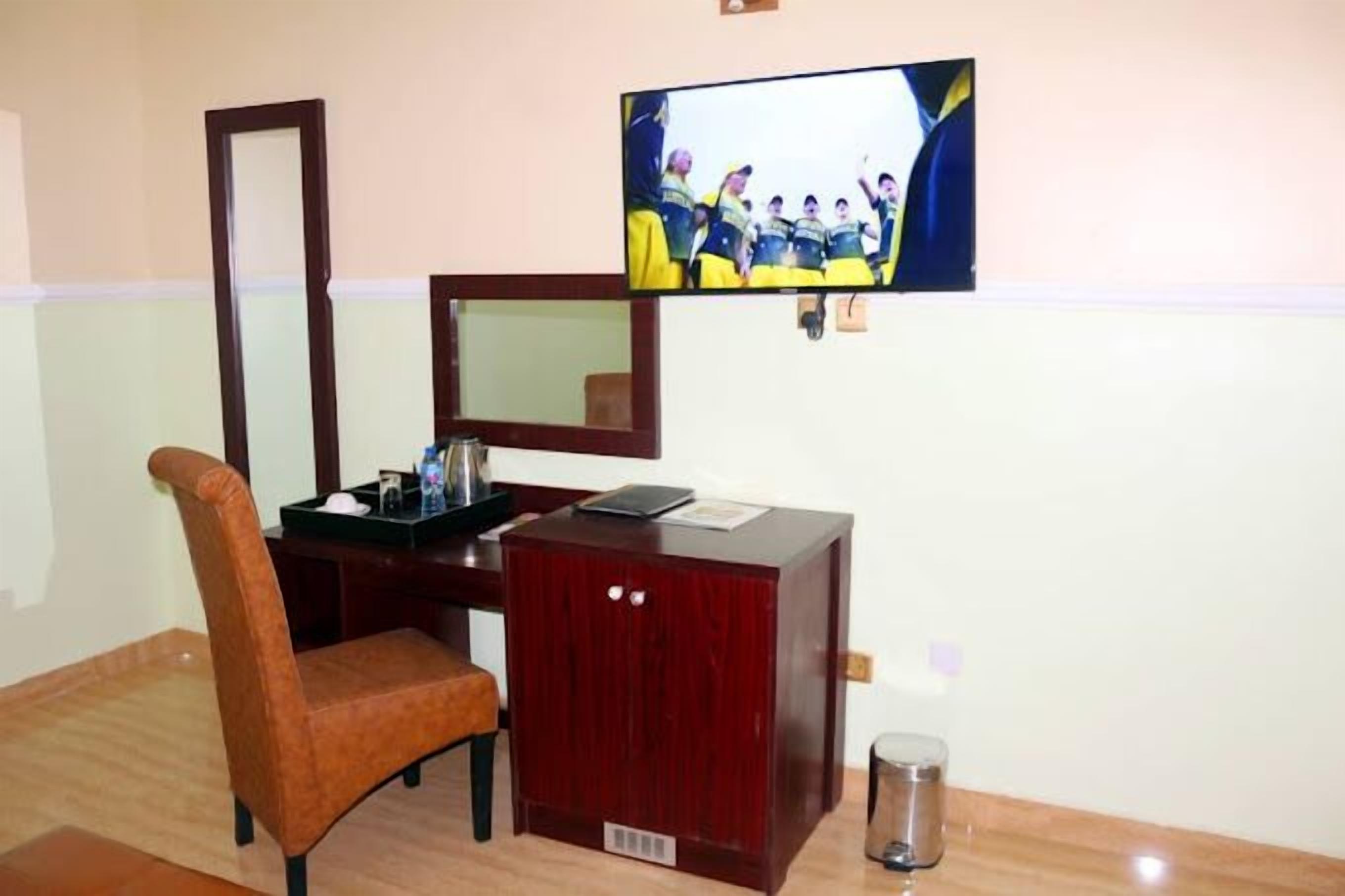 Une chambre d’hôtel avec un bureau en bois, une chaise, un téléviseur fixé au mur et un miroir.