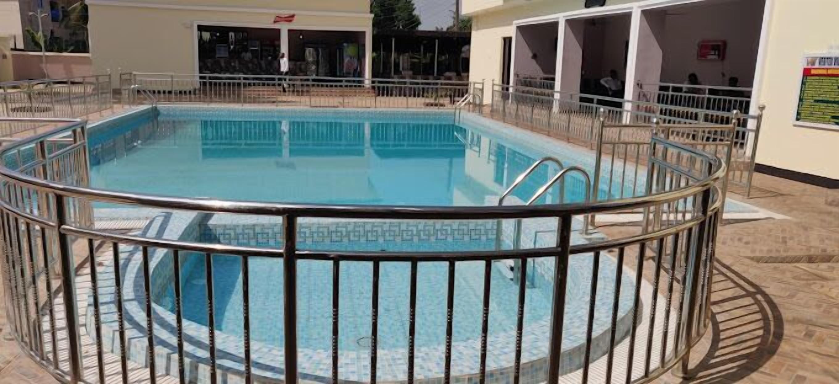 A round swimming pool with a metal railing, surrounded by a tiled deck.