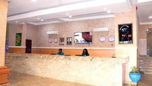 A reception area with a marble counter, framed pictures on the wall, and a television screen. - Vertex- View Hotel and Suites  (Awka)