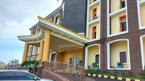 A multi-story building with a curved entrance, balconies, and a car parked in front. - Vertex- View Hotel and Suites  (Awka)