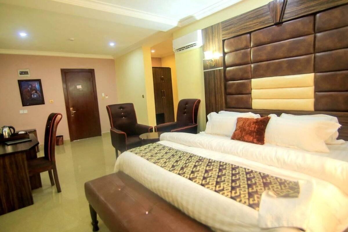 Une chambre d’hôtel avec un grand lit, deux chaises, une petite table et un bureau.
