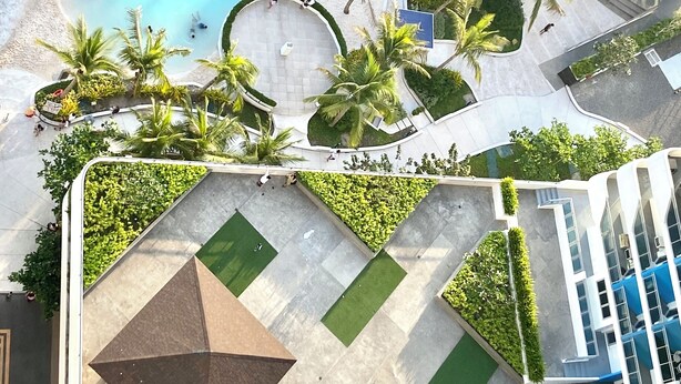 An aerial view of a resort with a large pool, palm trees, and a geometric plaza. - Cozy studio in beautiful San Fernando with AC, WiFi and Pet Friendly  (San Fernando)