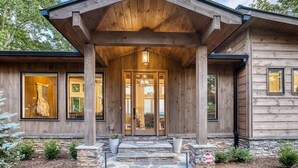 A modern log cabin with a prominent entrance, large windows, and a stone foundation. - Berry Refined - Luxury, views, hot tub, spacious (Morganton)