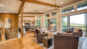 A spacious living area with wooden floors, large windows, and a view of the outdoors. - Berry Refined - Luxury, views, hot tub, spacious (Morganton)