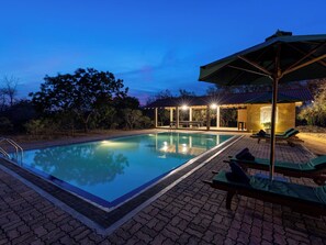A swimming pool with a covered seating area and lounge chairs. - Joe's Bungalow Yala (Kirinda)
