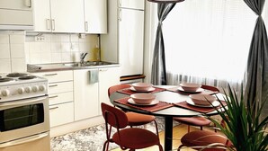 A modern kitchen with white cabinets, a stove, and a dining area with a table and chairs. - 1BR Demure Design Urban Living Space (Helsinki)