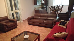 A living room with a brown leather sofa, a red sofa, and a glass coffee table.