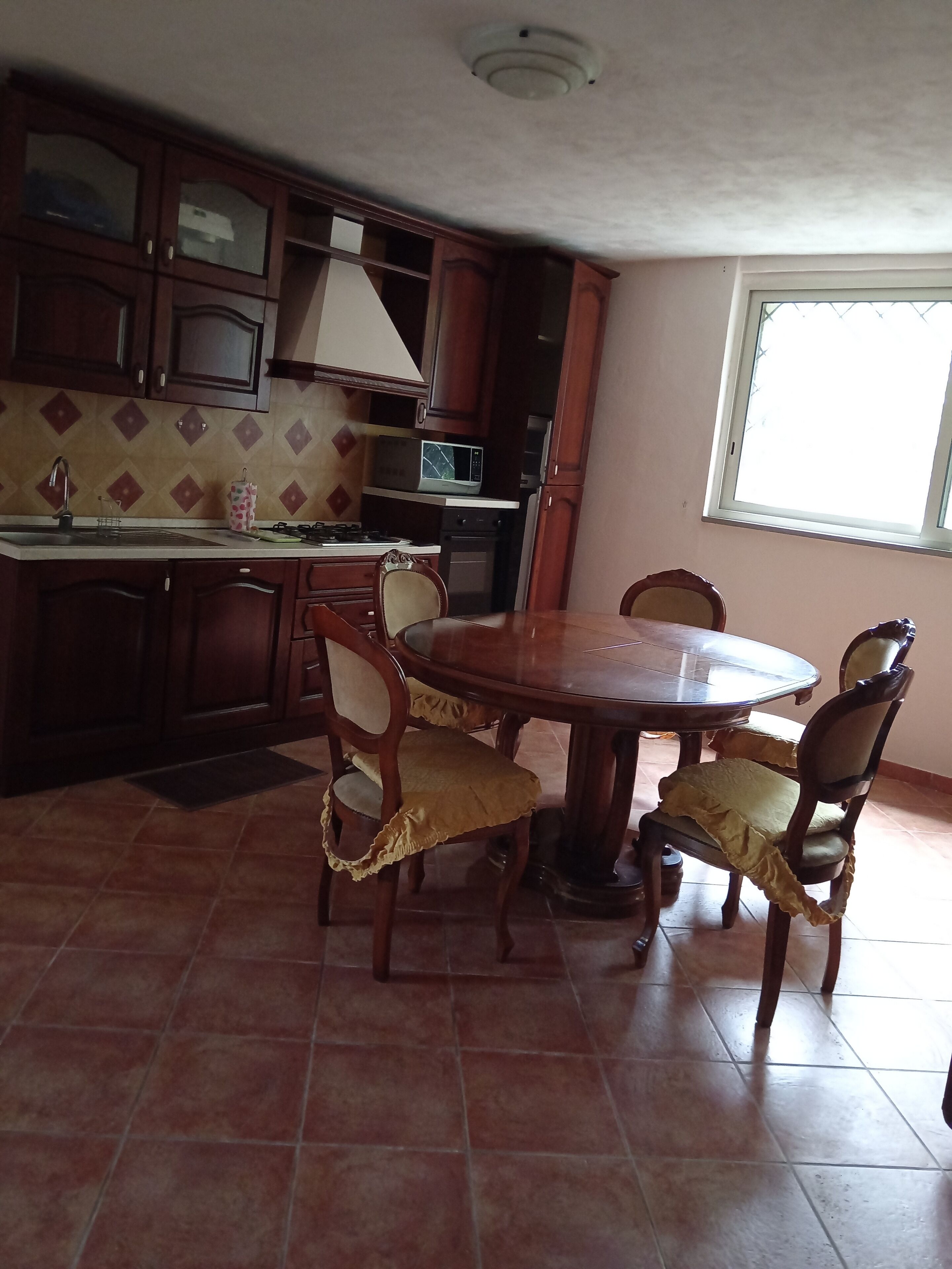 A kitchen with a dining table and chairs, a microwave, and cabinets.