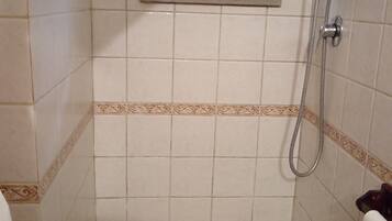 Ein kleines Duschbad mit gefliesten Wänden und einem Fenster über der Badewanne.