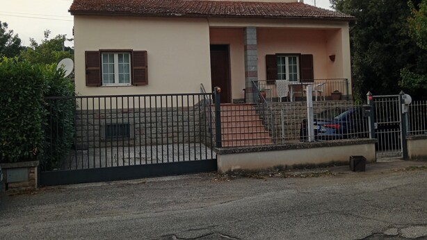 A single-story house with a tiled roof, a front porch, and a black metal fence.