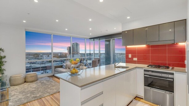 A modern kitchen with a large island, stainless steel appliances, and a red backsplash. - Adelaide Central Skyline Panoramic Suite Four (Adelaide)