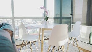 A modern room with a round table, white chairs, and a potted orchid. - Adelaide Central Skyline Panoramic Suite Four (Adelaide)