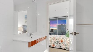 A modern bathroom with a large mirror, white tiles, and a vanity with a marble countertop. - Adelaide Central Skyline Panoramic Suite Four (Adelaide)
