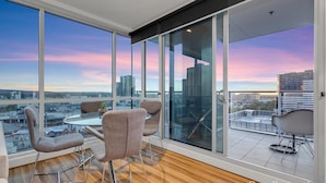 A modern interior with large floor-to-ceiling windows offering a city view. - Adelaide Central Skyline Panoramic Suite Four (Adelaide)
