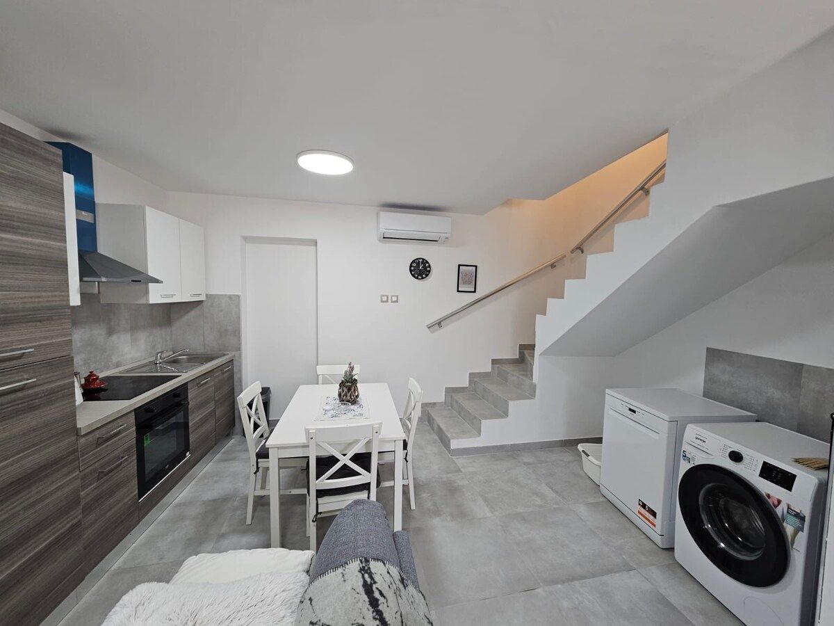 A compact kitchen with a dining area, a washing machine, and a staircase.