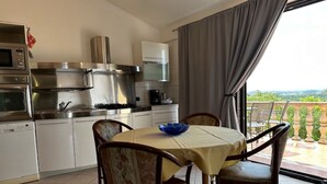 Une cuisine moderne avec des meubles blancs, des appareils en acier inoxydable et un coin repas comprenant une table et des chaises.